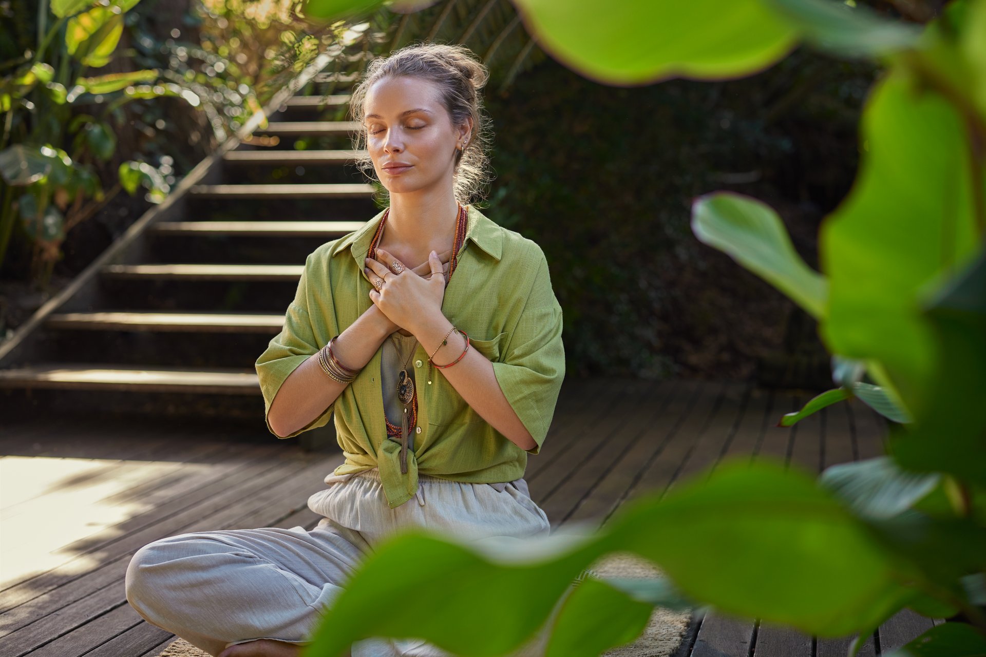 Mujer meditando en posición sentada con manos en el corazón